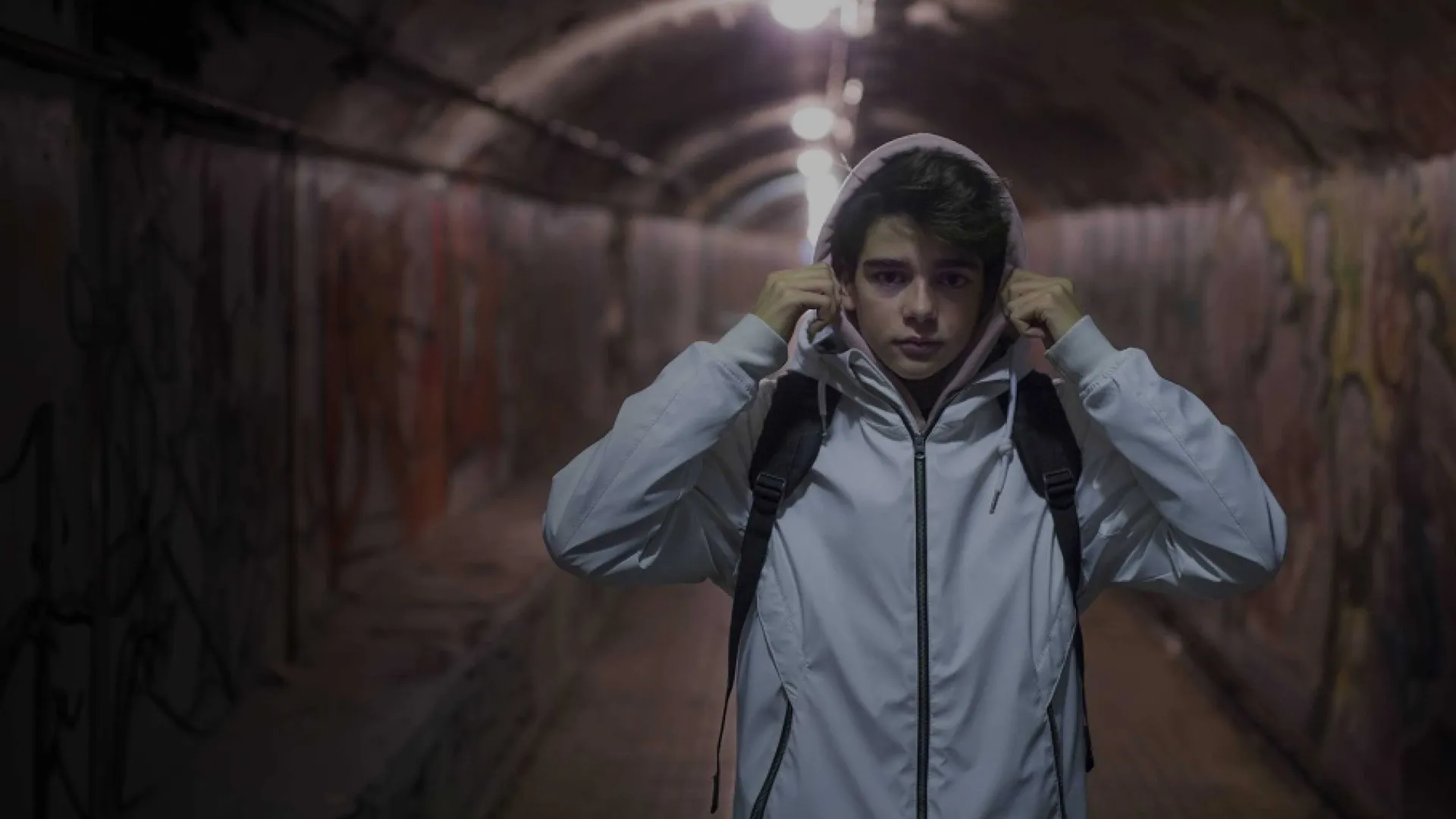 A man in a white jacket standing in a tunnel ready to embark on an exciting journey